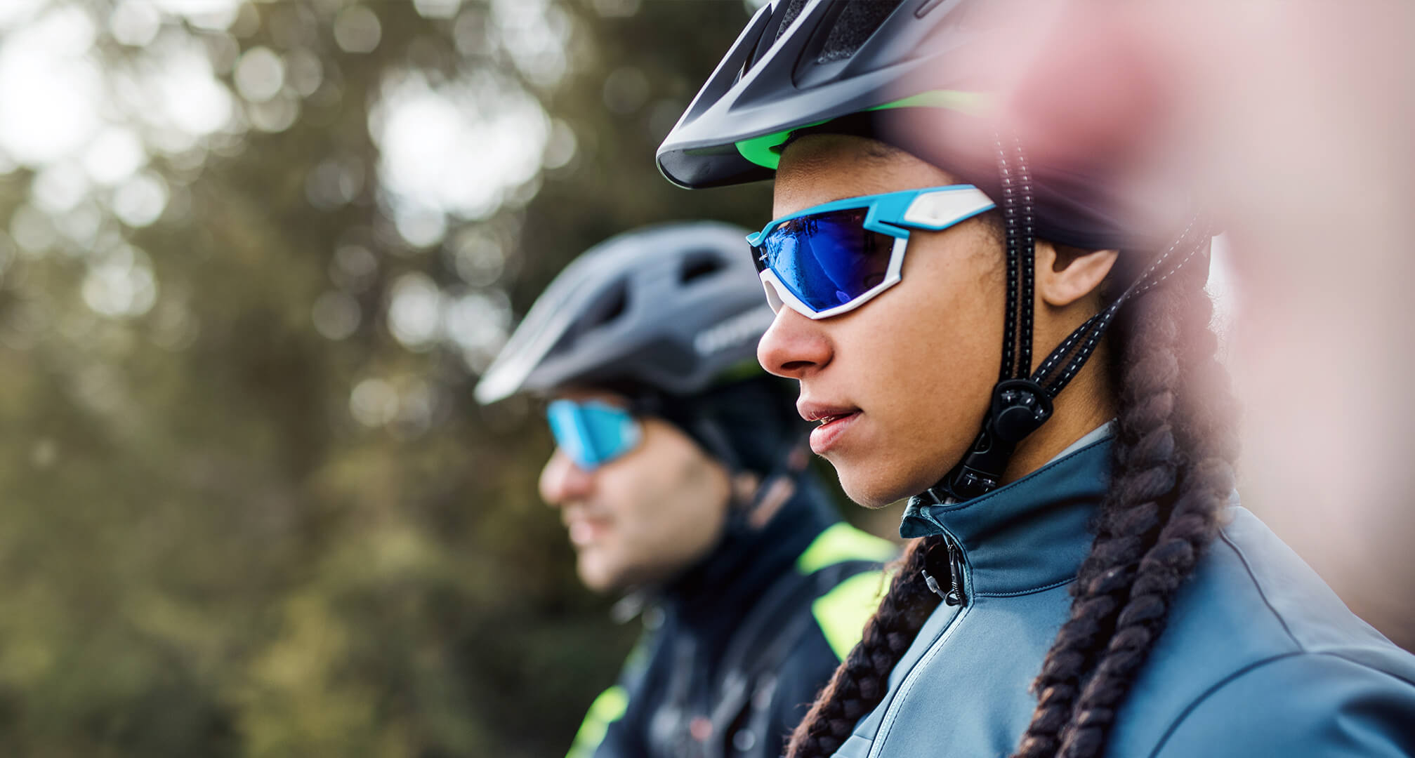 dvě osoby ve slunečních brýlích a cyklistických helmách